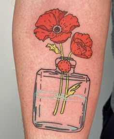 a red flower in a glass jar tattoo on the left calf leg, which is drawn with colored pencils