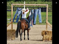 a woman riding on the back of a brown horse next to a pile of hay