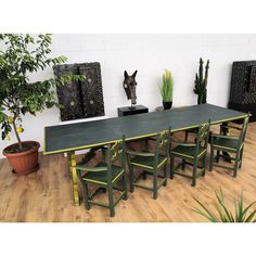 a long table with green chairs and potted plants next to it on a hard wood floor