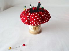 a red and white polka dot mushroom with pins in it