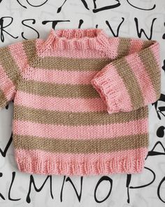 a pink and brown sweater sitting on top of a bed