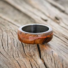 a wooden ring sitting on top of a piece of wood with an orange and black stripe