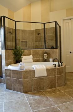 a bathroom with a large bathtub and tiled walls, along with a plant in the corner