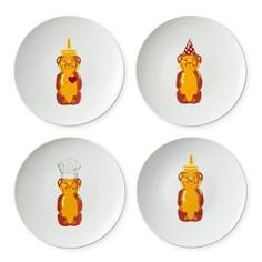 four white plates with yellow and red bear designs on the front, one has a candle in its mouth