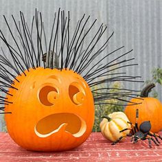 an orange pumpkin with spikes on it and a black spider sitting next to the pumpkin