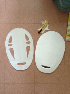 two white masks sitting on top of a floor next to a toothbrush and glue