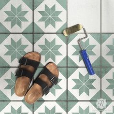 a pair of sandals and a paint roller on a tiled floor with green and white tiles