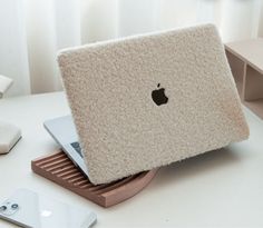 an apple laptop sitting on top of a wooden stand