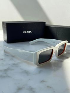 Brand new Prada PR06YS Sunglasses in White.Featuring a white acetate frame with dark grey lenses. Orange trim around lens.Silver metal Prada logos on temples.Size 53-21-145.100% authentic and unworn.Made in Italy.Box, case, cloth and paperwork included. Retail $520. White Square Frame Sunglasses With Polarized Lenses, Modern White Square Frame Sunglasses, Classic White Sunglasses With Uva Protection, White Square Frame Sunglasses With Mirrored Lenses, Modern White Sunglasses With Mirrored Lenses, Classic White Sunglasses With Tinted Lenses, Modern White Sunglasses With Tinted Lenses, Modern White Sunglasses With Uv Protection, Modern White Sunglasses With Uva Protection