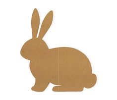 a cardboard cut out of a rabbit sitting on the ground with its head turned to the side