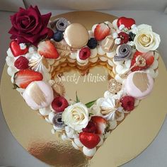 a heart shaped cake decorated with fruit and flowers on a gold platter in the shape of a heart