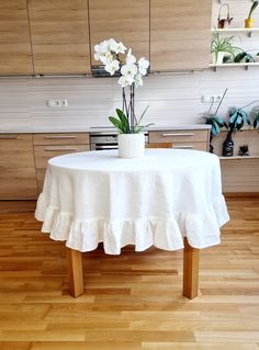 a white table with flowers on it in the middle of a wooden floored kitchen