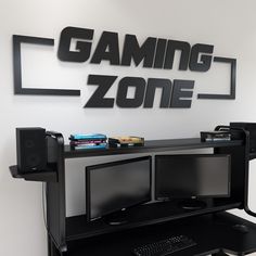 a computer desk with two monitors on it and a gaming zone sign in the background