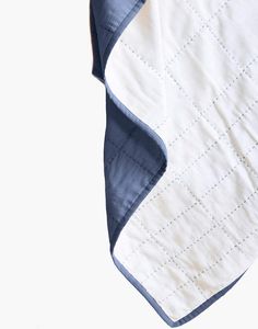 a white and blue quilted blanket laying on top of a table