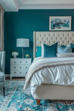 a bedroom with teal walls and white bedding, blue rugs, and an upholstered headboard