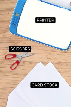 scissors, card stock and paper on a wooden table with the words printer in black