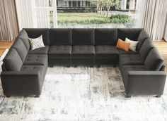 a large gray couch sitting on top of a rug in a living room next to a window