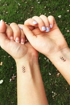 two hands holding each other with small tattoos on their wrist and the words love are written in cursive letters