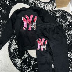 Size Medium Women’s Crewneck And Sweatpants, Really Soft On The Inside. Selling Because It Doesn’t Fit Me Right. The Sweatpants Have Elastic At The Bottom Like Joggers And They Have A Drawstring. There Is A Small Hole Inside The Left Pocket But Can Be Easily Sewn. The Design Is Pink Camouflage Ny Screen Printed On But It Has An Embroidered Looking Print Effect. I Am Willing To Sell The Pieces Separately If Anyone Is Interested Just Message Me Not Oversized - True Medium. Never Worn, Just Tried O Trendy Pink Crew Neck Set, Trendy Black Crew Neck Sets, Sporty Pink Streetwear Sets, Black Tracksuit With Letter Print For Loungewear, Winter Black Crew Neck Sets, Black Crew Neck Sets With Letter Print, Black Crew Neck Set With Letter Print, Black Letter Print Sets For Fall, Winter Black Graphic Print Sets