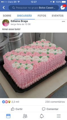 a pink and white cake sitting on top of a black pan covered in frosting