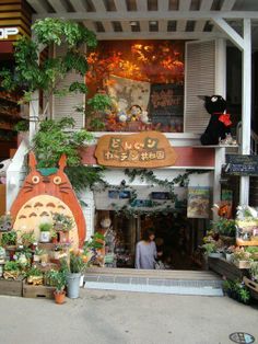 a store with lots of plants and stuffed animals on the front porch, including a totoro