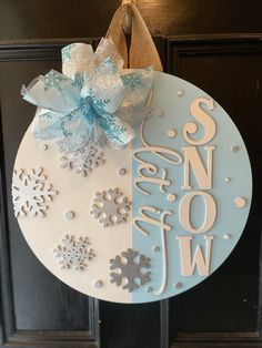 a door hanger decorated with snowflakes and the word snow written on it