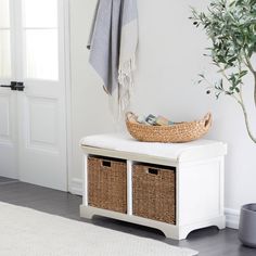 a white bench with two baskets and a towel on it next to a potted plant