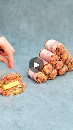 a hand reaching for some food wrapped in plastic on the ground next to another person's finger