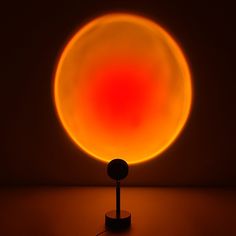 an orange and red object is lit up in the dark with a black stand underneath it