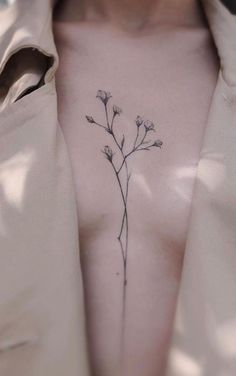 a woman's chest with a small flower tattoo on her left side ribcage