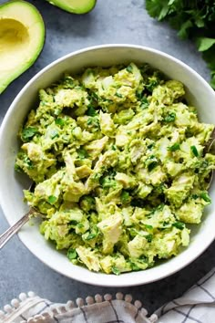 a bowl filled with guacamole next to an avocado