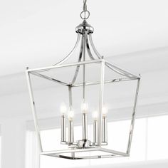 a chandelier with four lights hanging from it's ceiling fixture in a white room