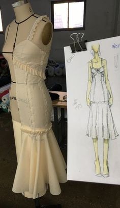 a mannequin with a dress on it next to a piece of paper and a drawing