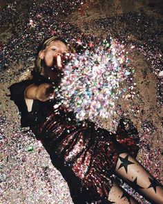 a woman laying on the ground surrounded by confetti and stars, with her mouth open