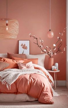 an orange and white bedroom with peach colored bedding, pink flowers and hanging lights