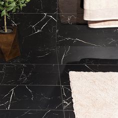 a bathroom with black marble flooring and white rugs