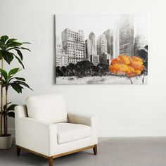 a white chair sitting next to a potted plant in front of a painting on the wall