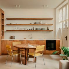 a table and chairs in a room with open shelves on the wall above it, next to a couch