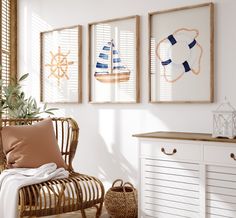 three framed pictures hang on the wall above a wicker chair in a white room