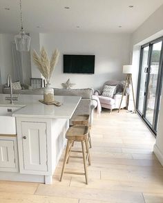 a kitchen island with stools in front of it and a television mounted on the wall