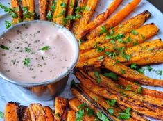 a white plate topped with cooked carrots next to a dipping sauce