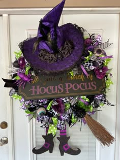 a purple witches hat wreath hanging on the front door with witch legs and green polka dots