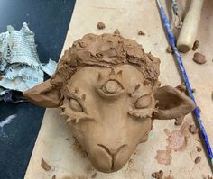 a clay sculpture of a sheep's head on a table next to other items