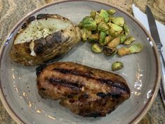 a plate with meat, potatoes and brussel sprouts sitting on it