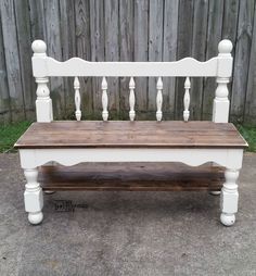 a white bench sitting on top of a cement ground next to a wooden fence and grass