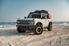 a white truck parked on top of a sandy beach