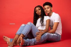 a man and woman sitting on the ground posing for a photo with their arms around each other