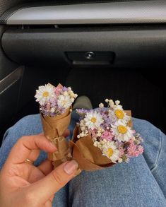 two people holding flowers in their hands while sitting in the back seat of a car