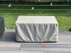 an outdoor grill cover sitting on top of a wooden deck