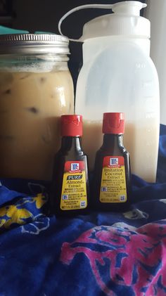 two bottles of liquid sitting on top of a blue blanket next to a bottle of milk